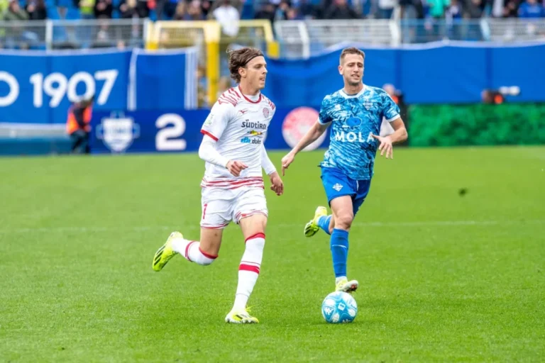 Como and Südtirol players in action during an Italian Cup match, with the player in blue controlling the ball under pressure from the opponent in white.