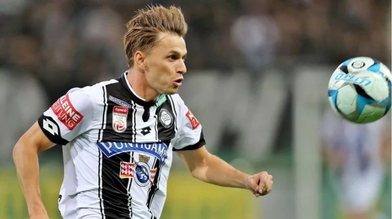 Sturm Graz player in black and white kit focuses on the ball during a football match in the Austrian Bundesliga.